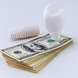 Model implant on money representing the cost of dental implants
