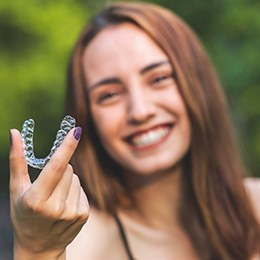 young woman holding two clear aligners 