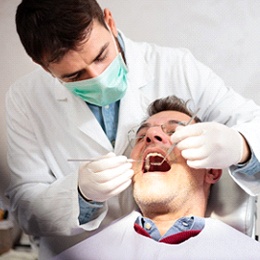 A dentist examining a male patient’s oral cavity to check for abnormalities