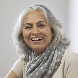 An older woman wearing a polka dot scarf and smiling after undergoing a root canal