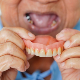 A woman holding a denture away from her mouth