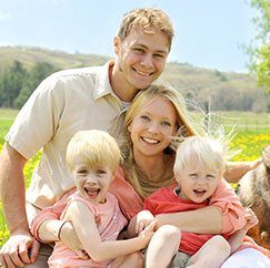 Family of four smiling outside after preventive dentistry visit