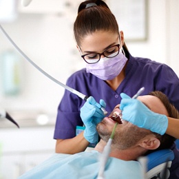 A dental hygienist performing a thorough cleaning on a male patient