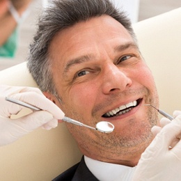 An older man lying back in a dentist’s chair in preparation tooth-colored fillings in Arlington