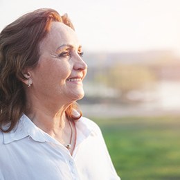 woman smiling while standing outside 