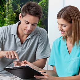 A dental staff member discussing payment options with a male patient in Arlington