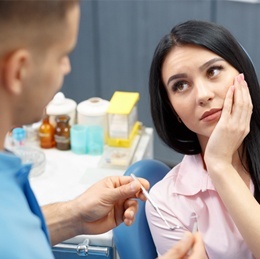 Woman holding jaw in pain due to failing dental implant