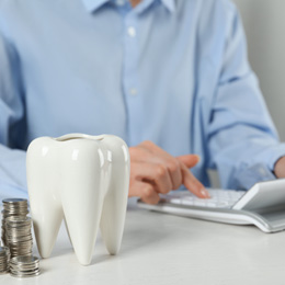 Person on calculator with coins and tooth nearby 