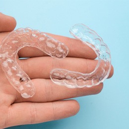 person holding two clear aligners  