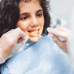 A dentist giving an Invisalign tray to a teen girl 