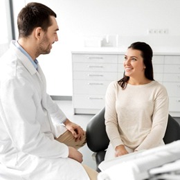 A male dentist talking to a female patient about the process of an oral cancer screening in Arlington