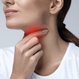 A woman holding her throat while a red patch radiates to signify pain