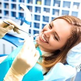 A young woman smiling while seated in the dentist’s chair and waiting for the dentist to check her smile