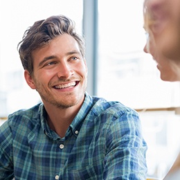 man smiling while talking to friend 