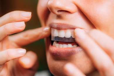 Woman using whitening strips in Arlington 