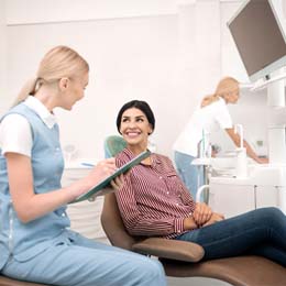 A woman looking at her whiter, brighter smile in the mirror during a regular checkup