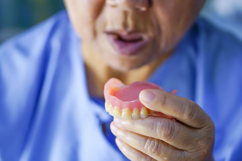 an older man holding his denture in his hand