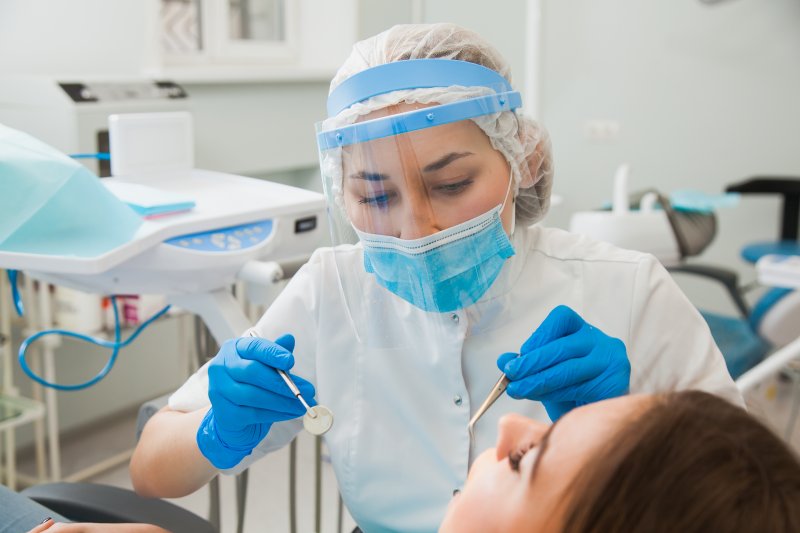 a dentist wearing personal protective equipment while caring for a patient’s smile