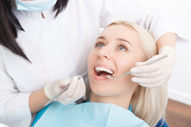 a young female with blonde hair having a dental checkup performed by her dentist