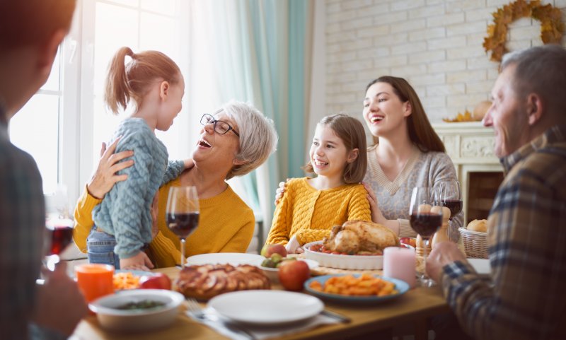 an older woman smiling and looking at her granddaughter while seated at the Thanksgiving table