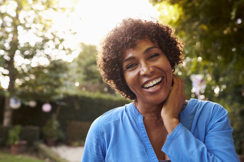 a middle-aged woman wearing a blue blouse and smiling while standing outside