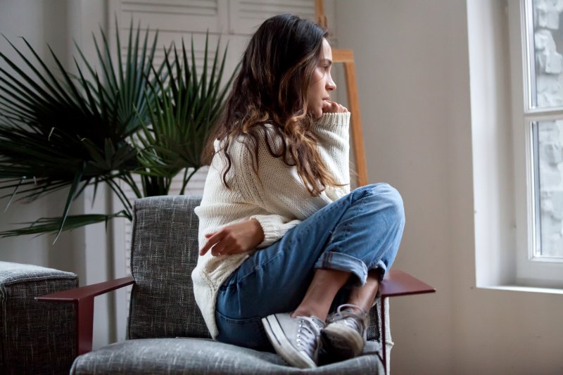 a woman sitting in a chair curled up and appearing anxious and tired