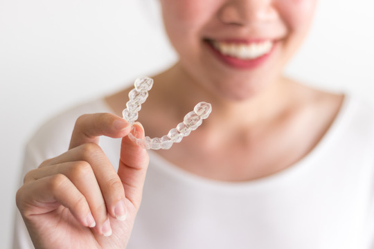 young woman holding clear aligner 
