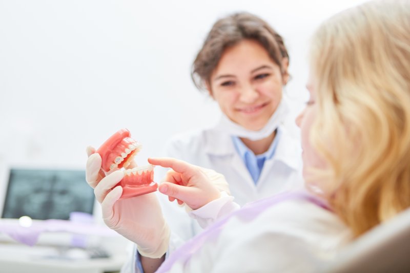 A dentist showing model dentures to a younger adult