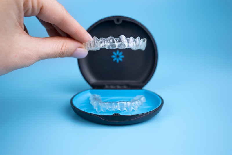 A hand placing an Invisalign tray in a carrying case
