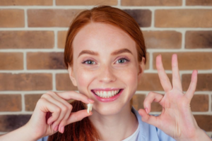 Woman holding a knocked-out tooth and smiling